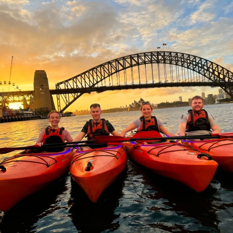 an orange boat on a body of water with Sydney Harbour Bridge in the background