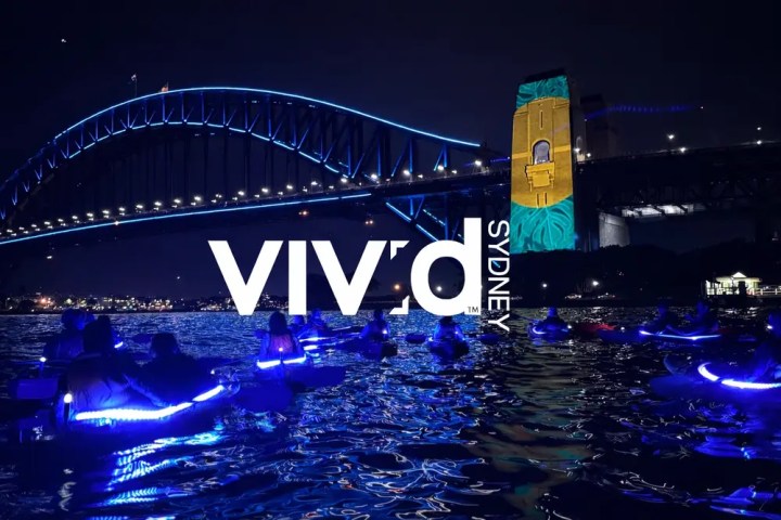 Kayaks with blue lights under Sydney Harbour Bridge during Vivid Sydney festival at night.